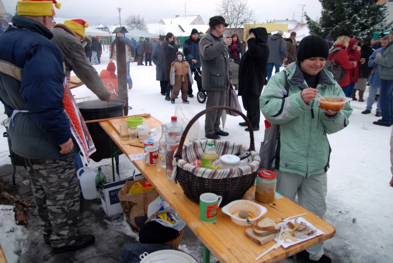 a woman eating food next to a table that is covered in snow