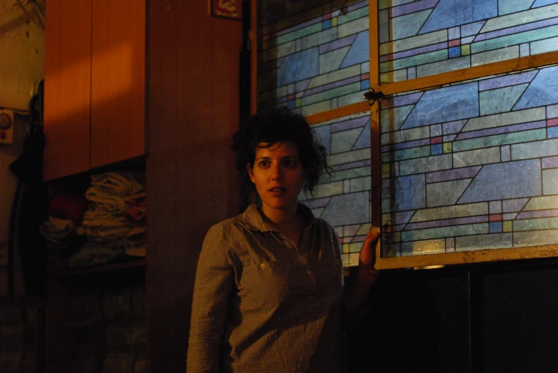 a woman stands next to a stained glass window