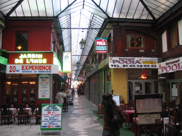 a woman walks down a street lined with stores