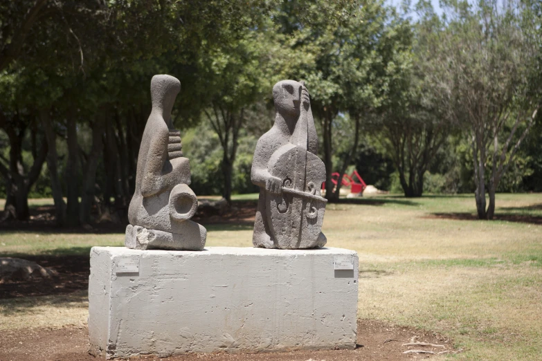 two statues sitting in the grass of a park