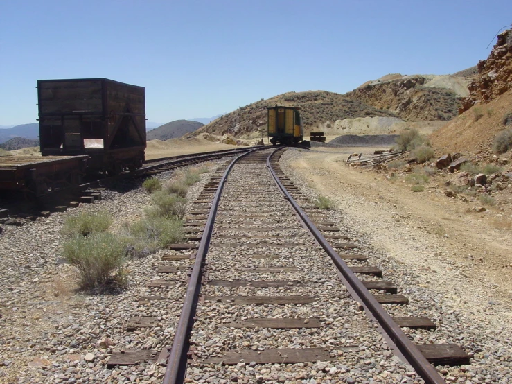 two freight train carts on tracks in the desert