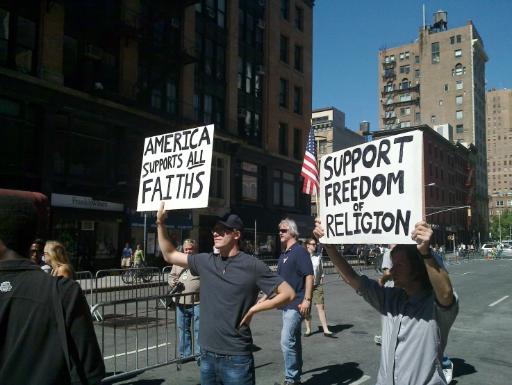 two men hold signs while walking on the street