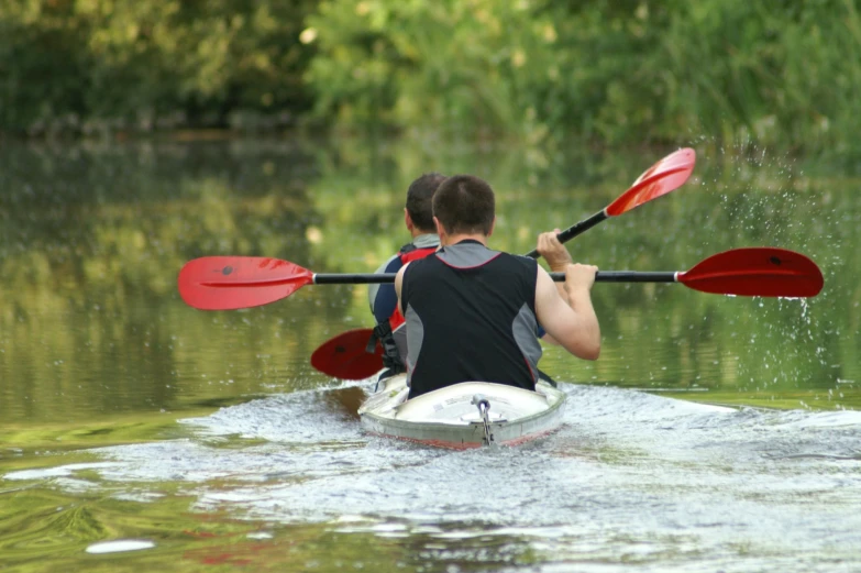 two men paddling on their canoes down the water