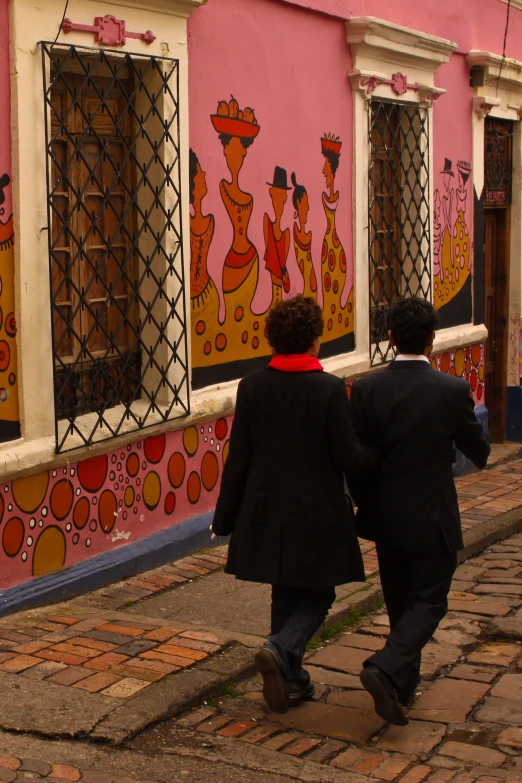 the back view of two men walking down a street