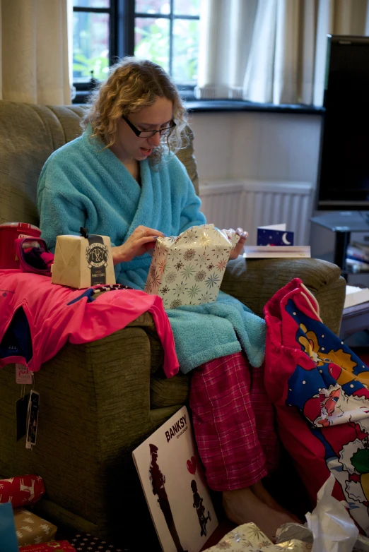 woman reading on sofa in decorated room with presents