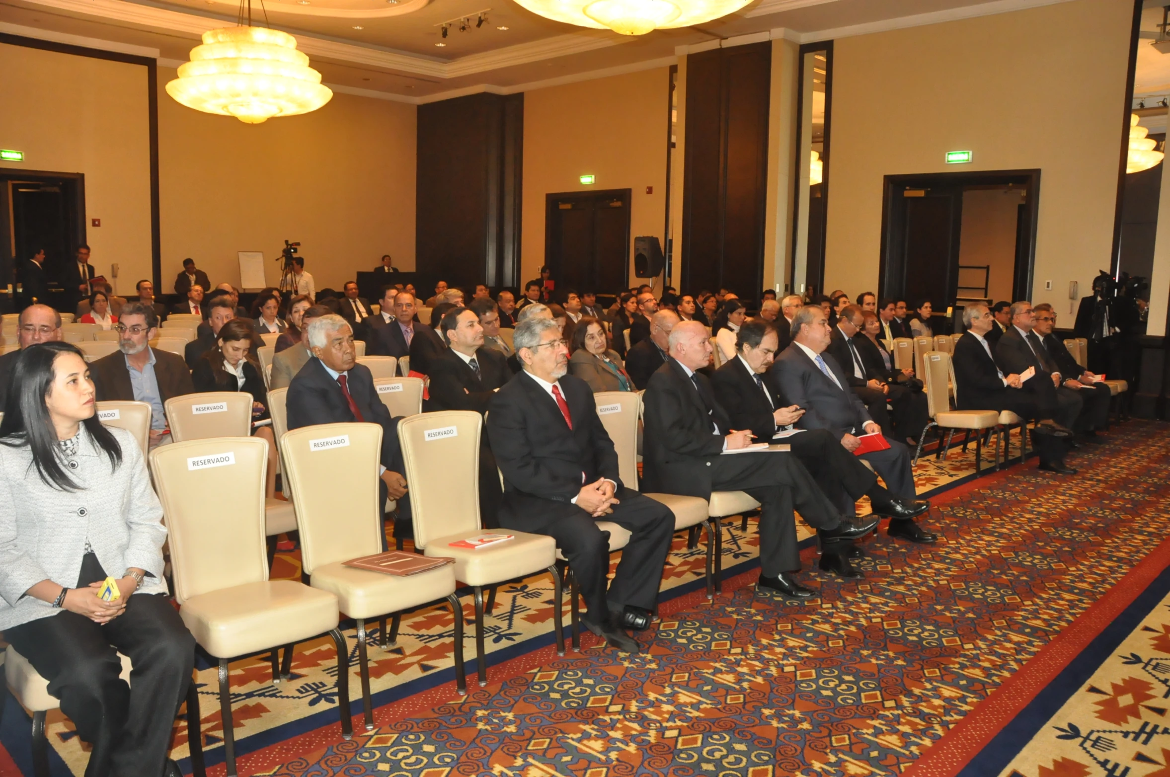 a group of people in suits and ties are sitting down with their backs turned towards the crowd