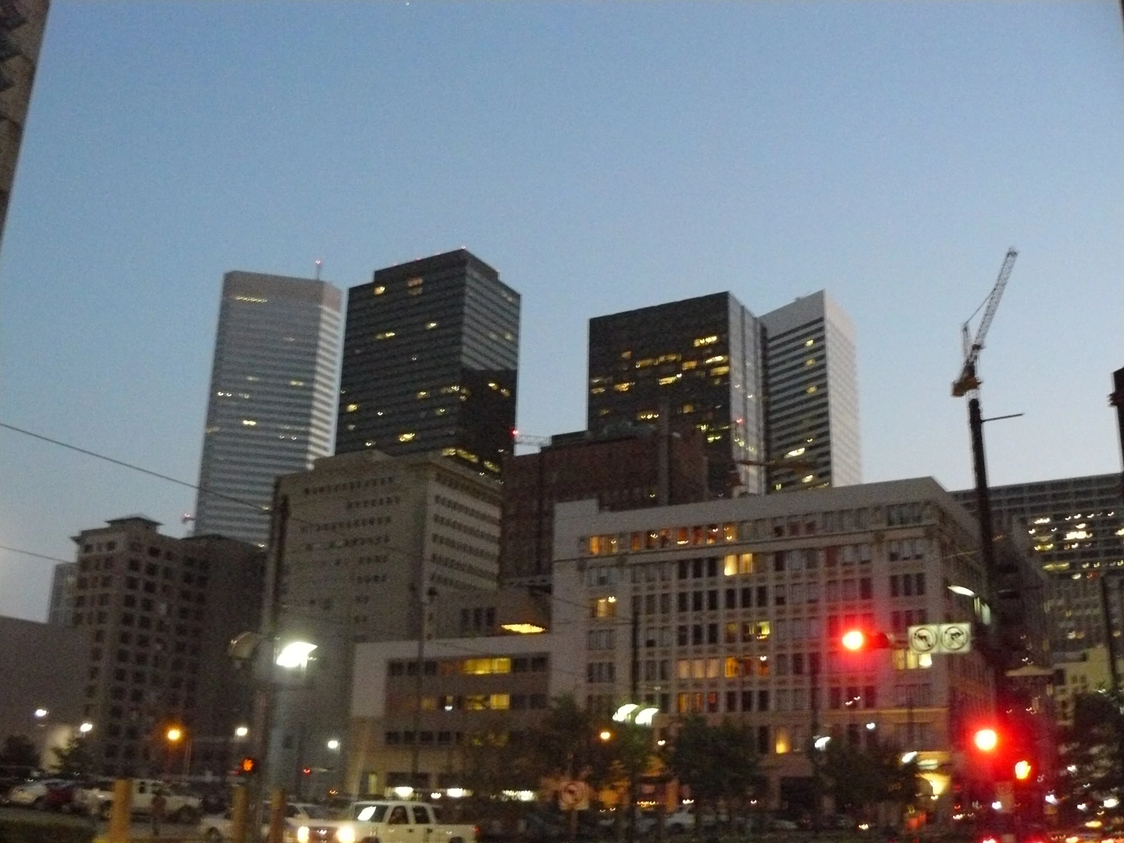 cars at dusk drive through downtown on a busy city street