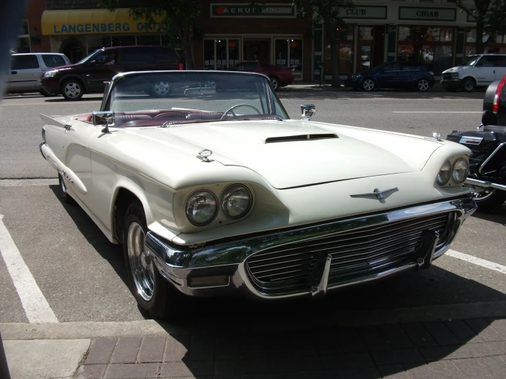 an old model white convertible car is parked next to other vehicles
