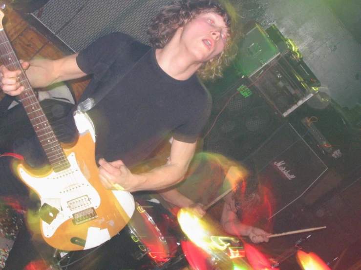 a man standing with a guitar in his hand and blurred images around him