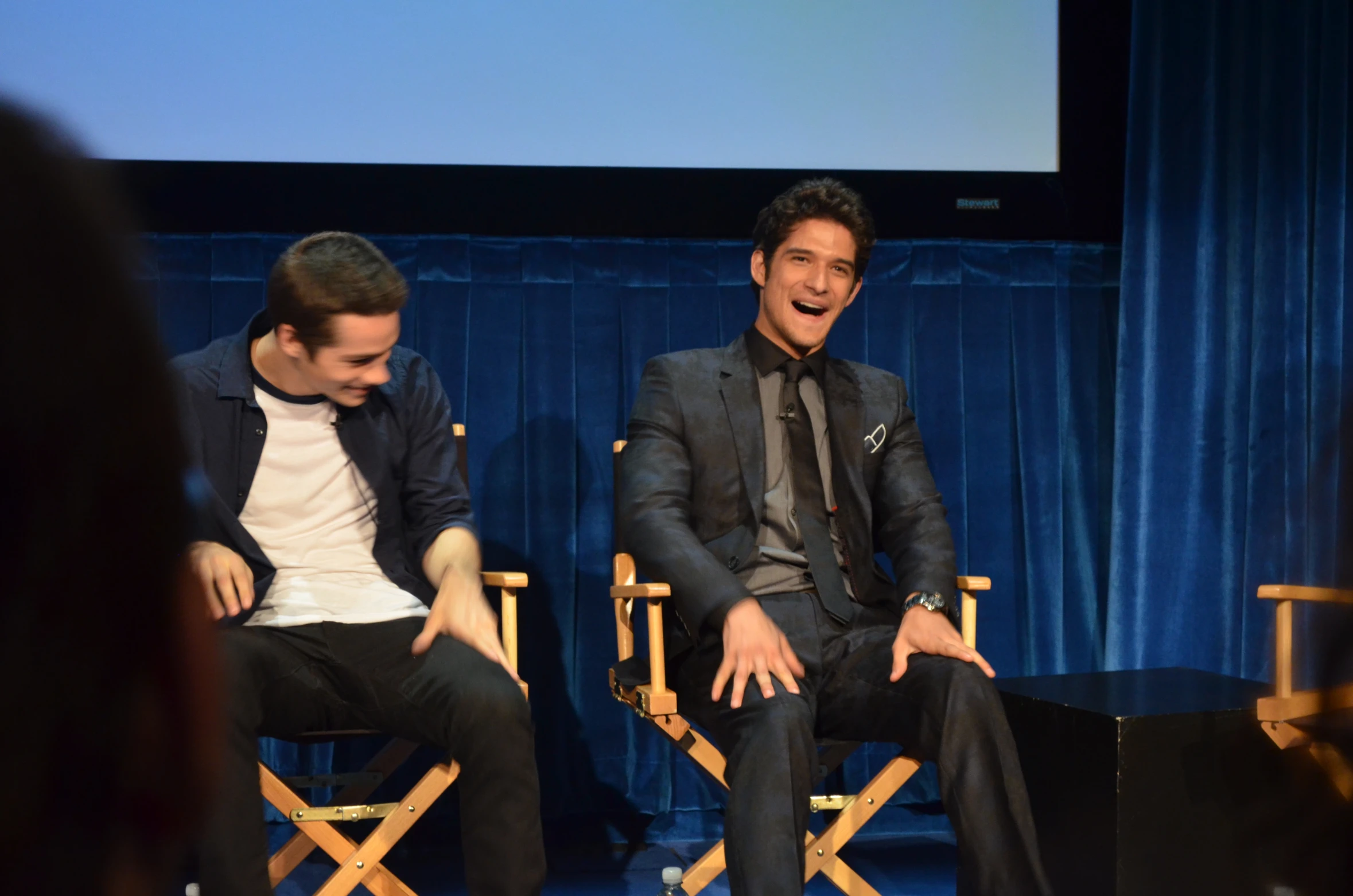 two men sitting in chairs with one making a silly face