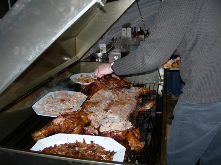 a person wearing an apron pulls some food out of the oven
