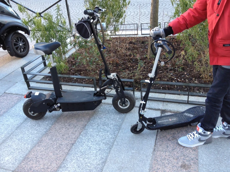 someone standing next to two electric scooters on the stairs