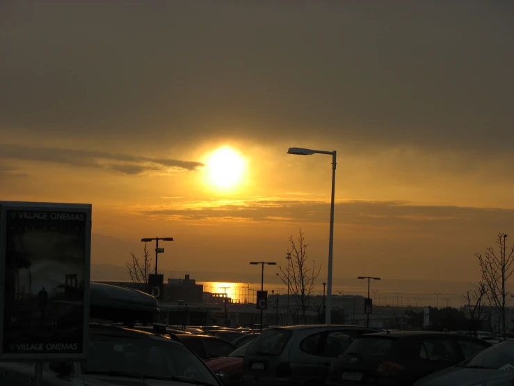 the sun rising behind clouds in a parking lot