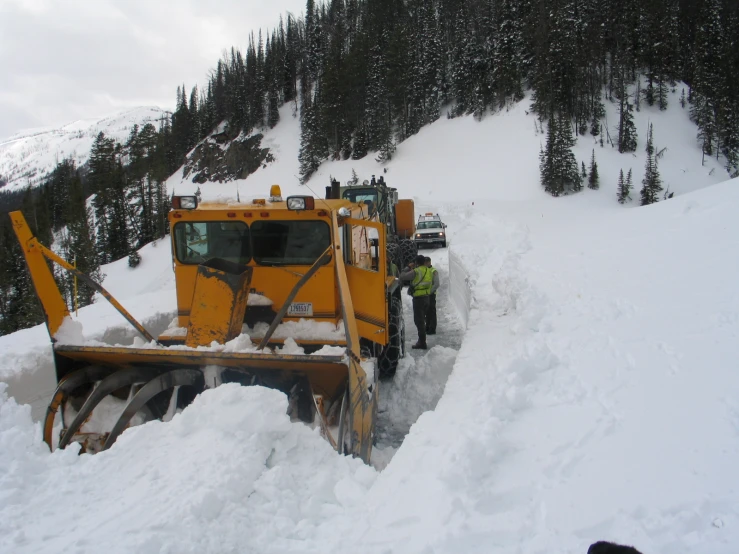 a man in skis is standing in the snow next to a snowplow