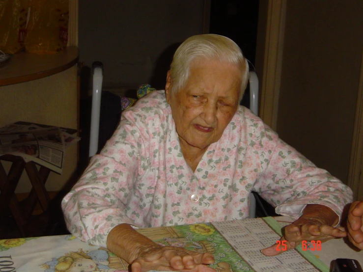 an older lady wearing pink is sitting at the table