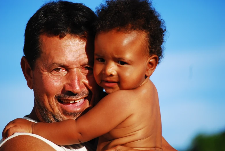 man holding up his child to be hugged