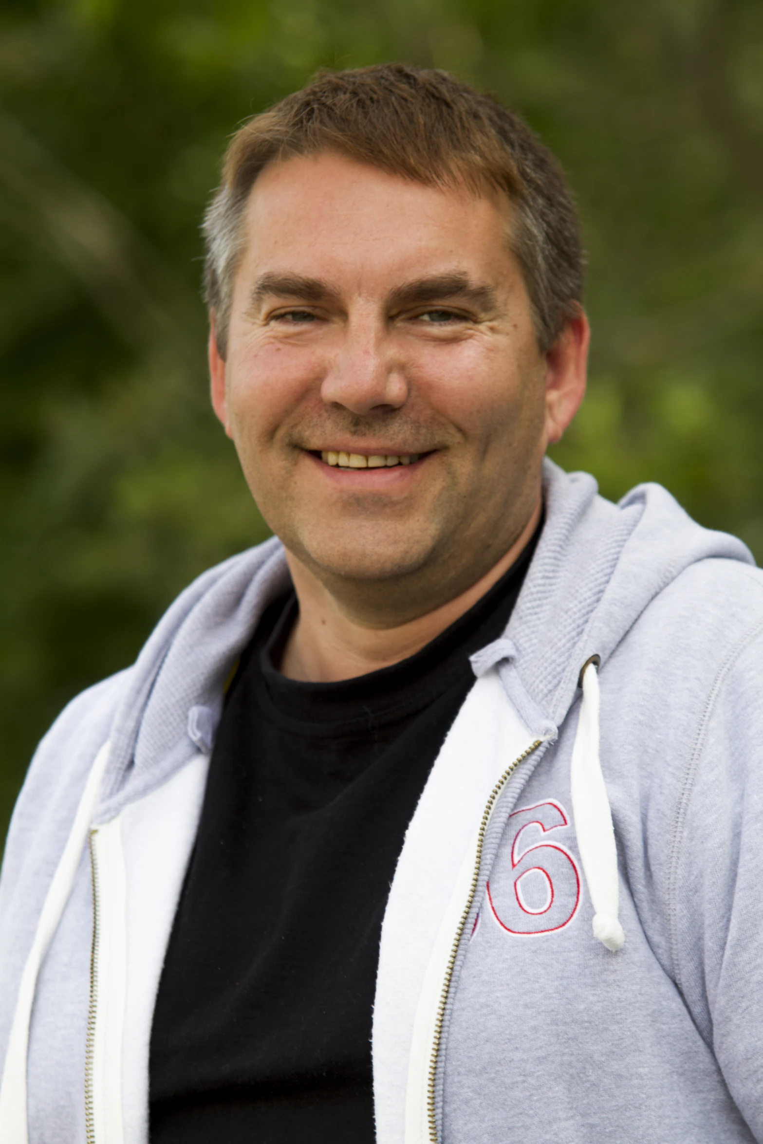 a man is posing for a picture in front of some trees