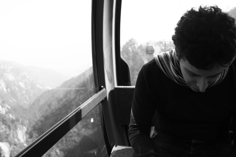 a black and white po of a man sitting on a cable car looking at his watch