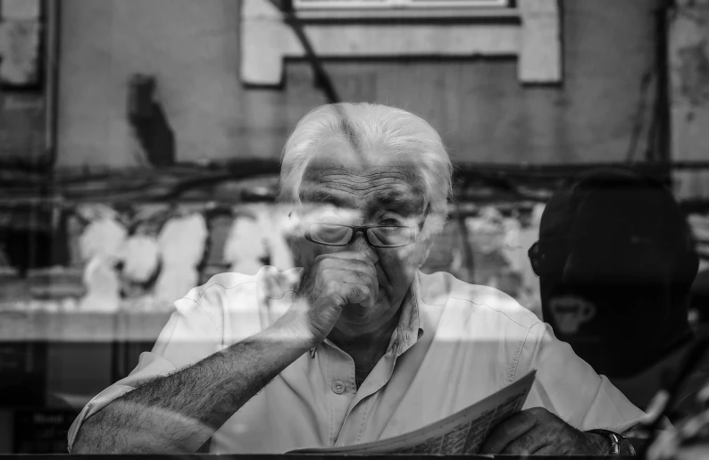 man standing behind glass looking at reflection of other people