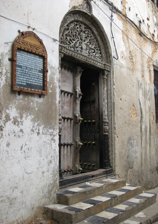old door with a plaque near stairs on wall