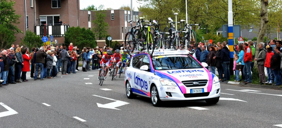 a car carrying bikes on it's back drives down the street