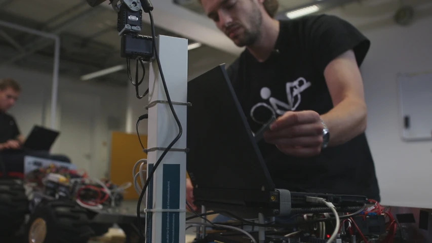 two men in an assembly line working on the same computer