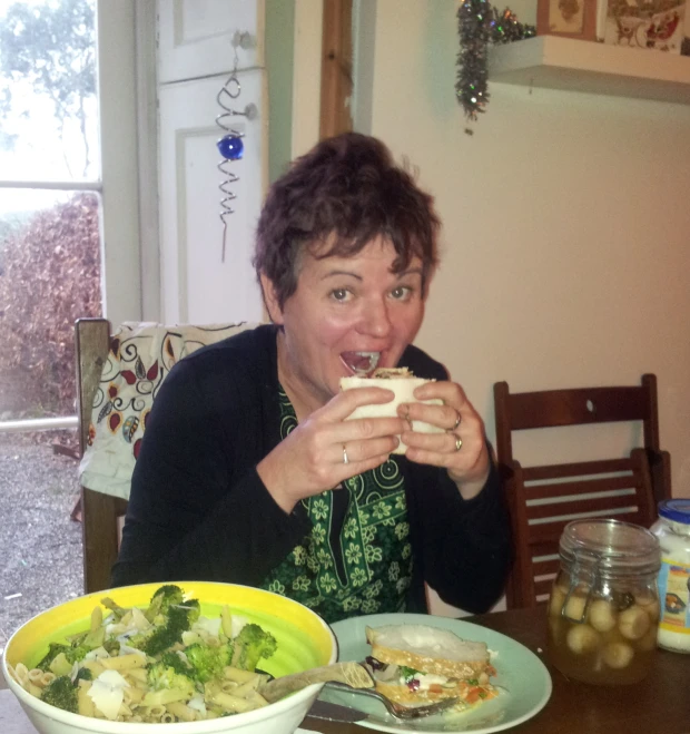 a woman in black jacket eating and drinking from container