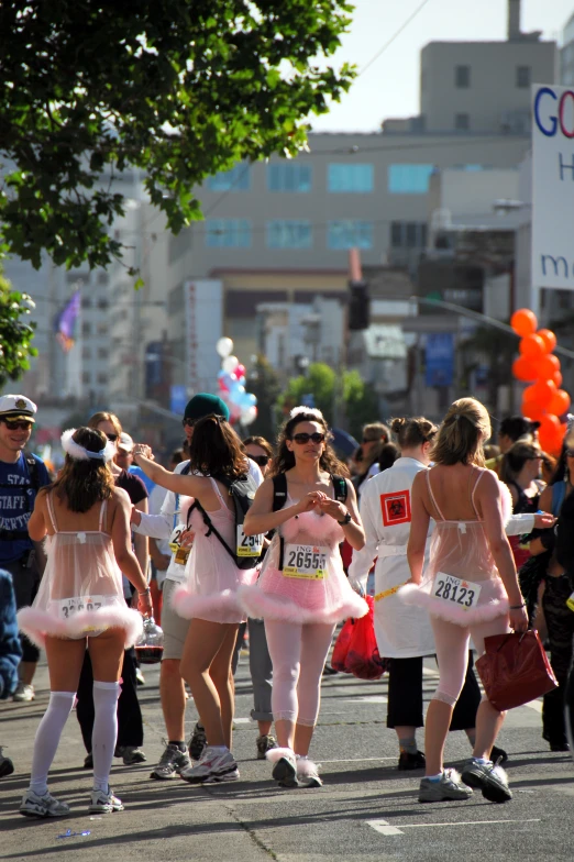 several women are walking on a city street with tutus