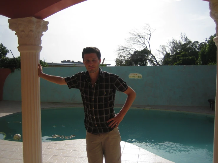a man posing by an open - air swimming pool