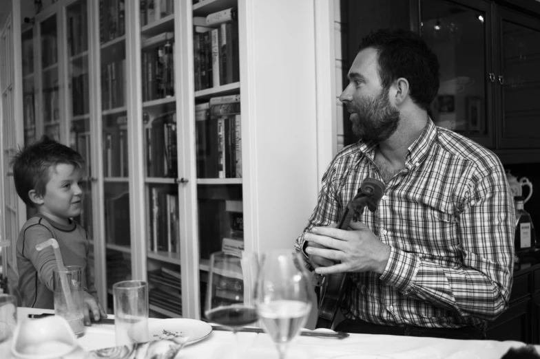 black and white pograph of man and child in front of bookcase