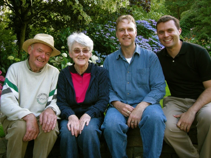 four men sit and smile in a garden