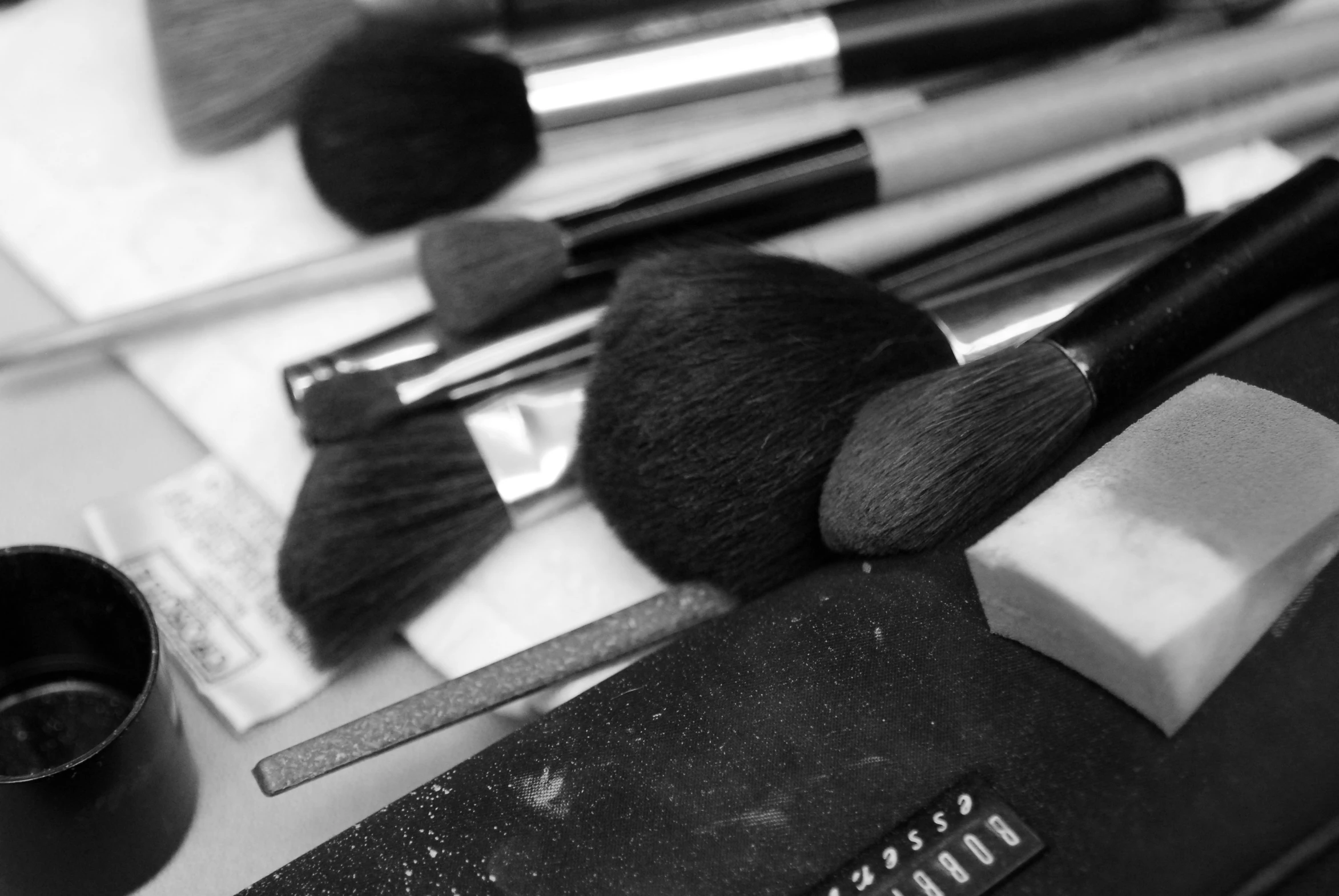 a black and white po of some makeup brushes and a can of paint