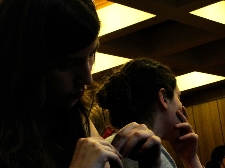 two young women sitting in a room talking and looking