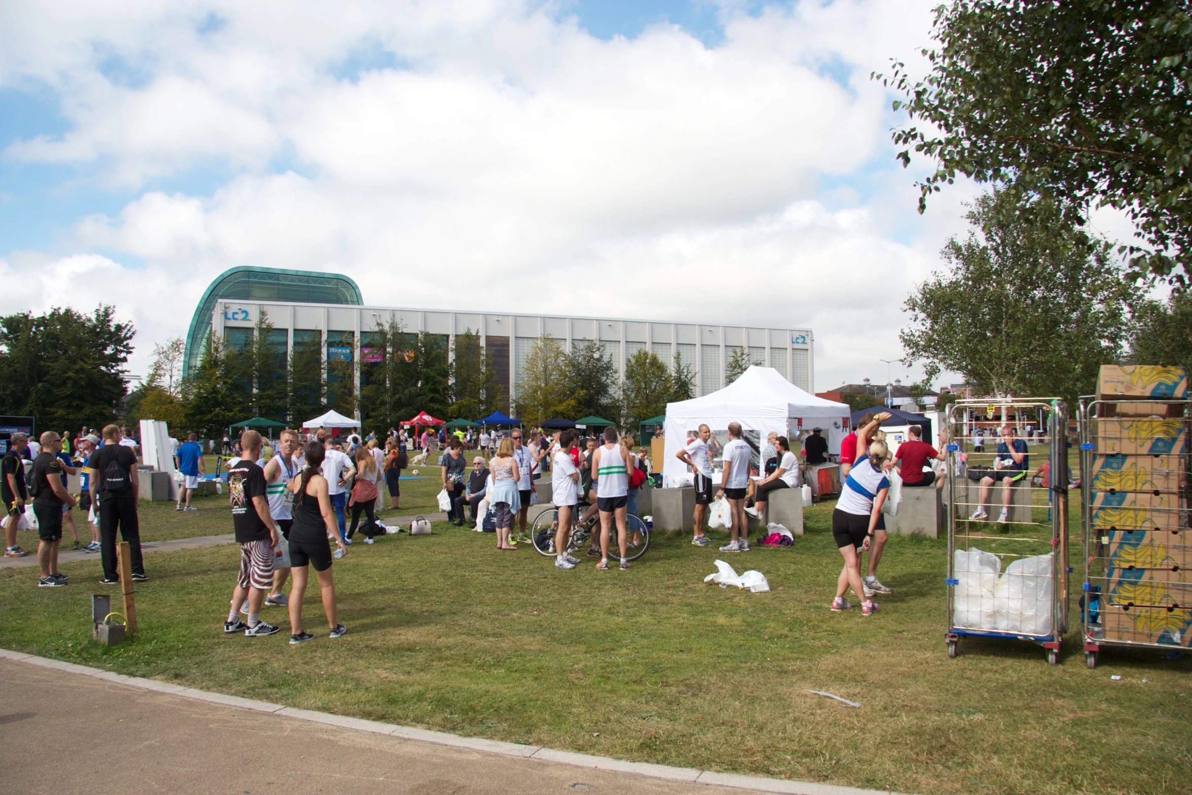 an outdoor event with a lot of people standing and talking in the grass