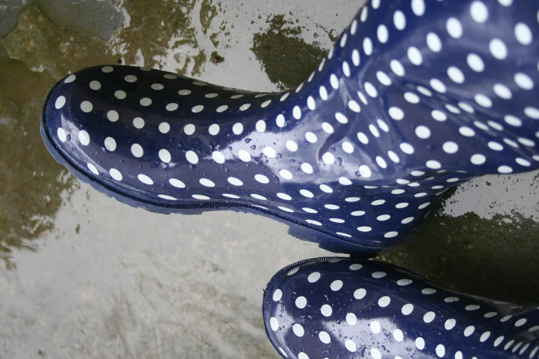 woman's feet wearing black and white dots well worn rain boots