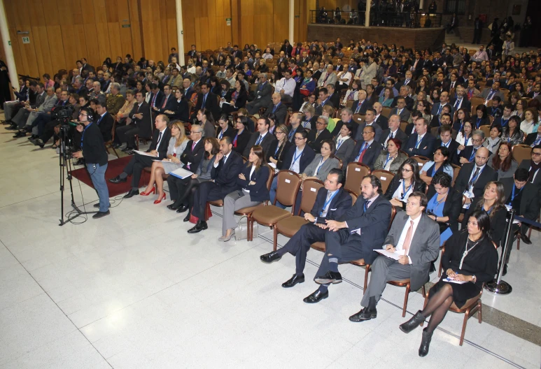 a large group of people sit in front of microphones and chairs