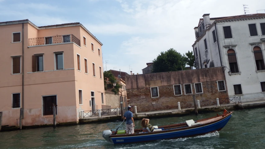 a man standing on the back of a blue boat