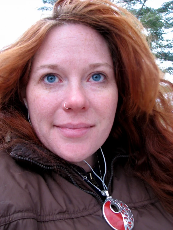 this is a woman wearing a brown jacket and smiling