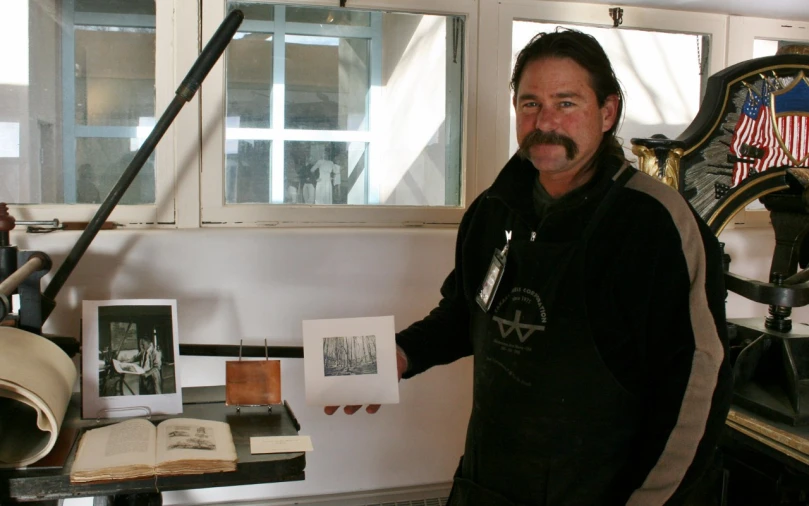 the man is standing by his desk holding a book