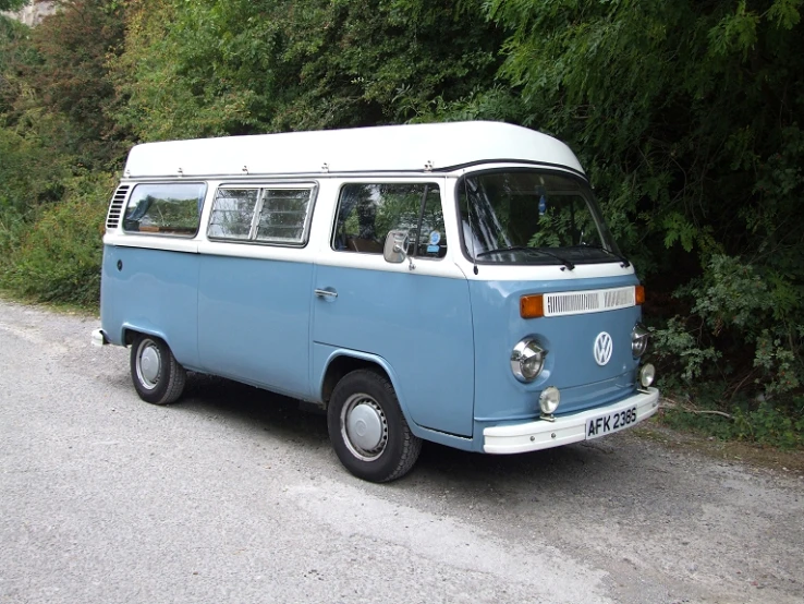 a vw bus is parked on the street by some bushes