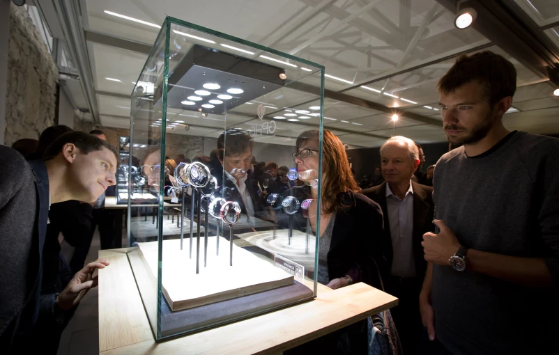 some people are gathered around a display case with watches