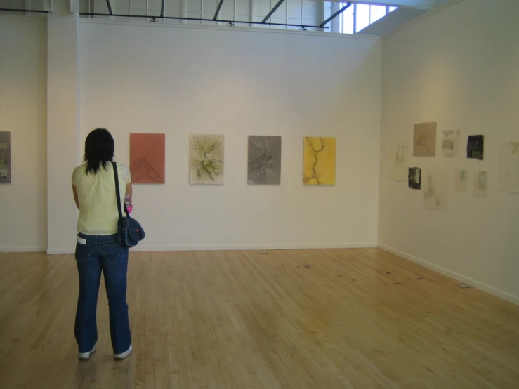 a woman is looking at art hanging in a gallery