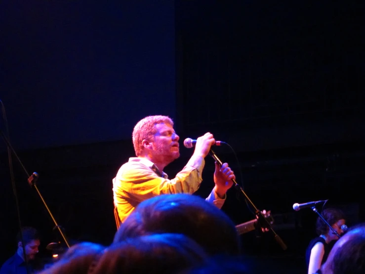 man singing into a microphone on stage during a concert