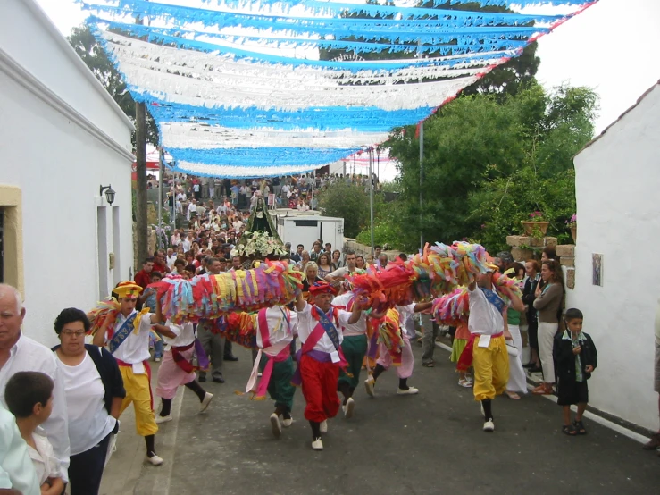 group of people wearing brightly colored clothing in street with streamers