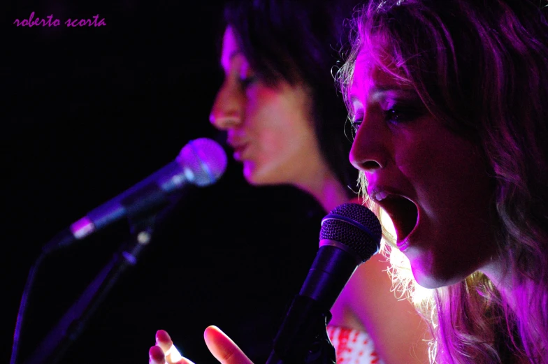 two people singing in front of a microphone