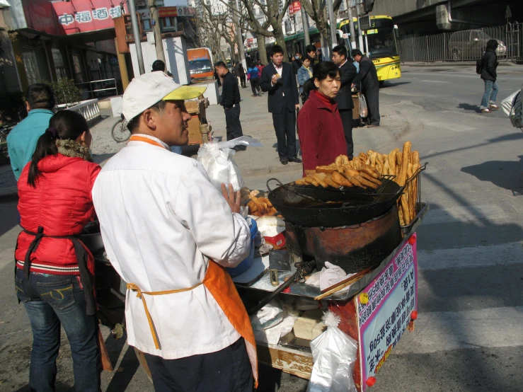 people on the sidewalk, one of which is selling some food