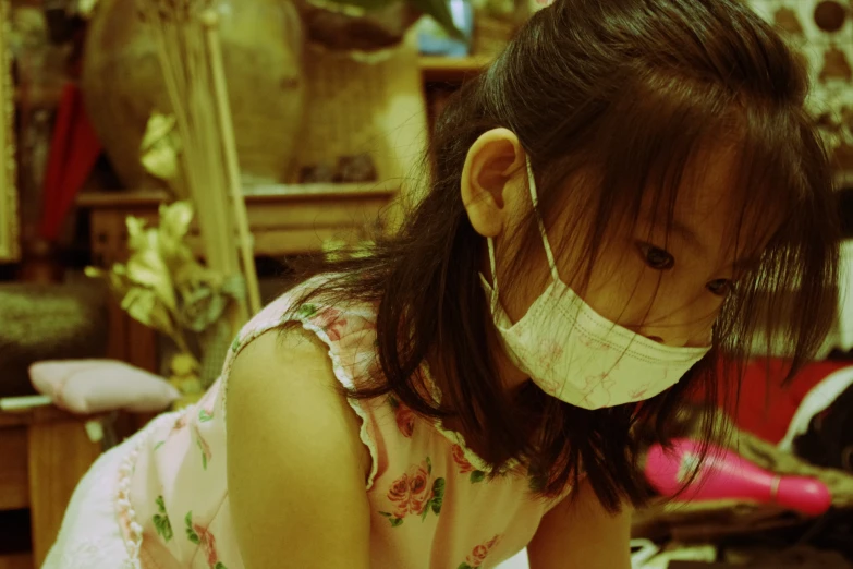 a  wearing a surgical mask in her messy room