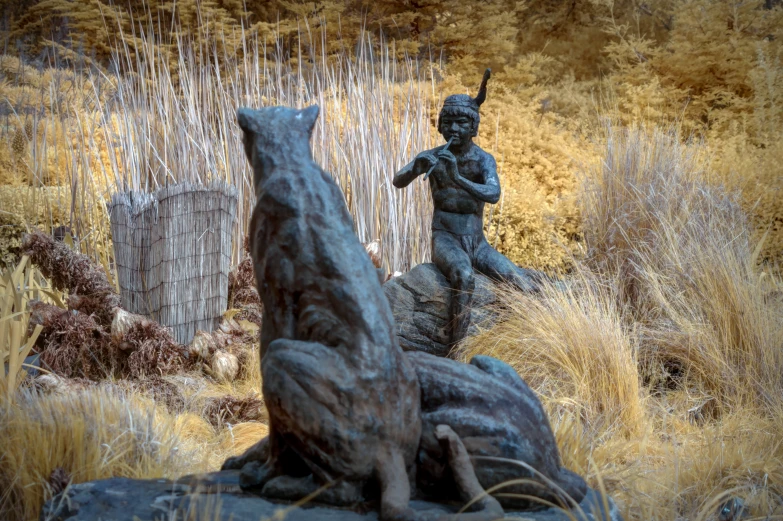 a bronze statue of a boy with a dog is posed by some other statues