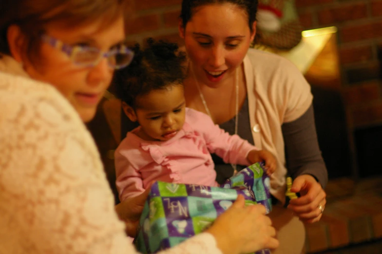 two women and a little girl holding a green wrapped present