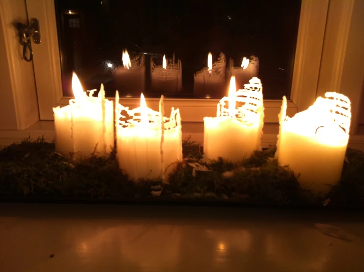 lit candles on a counter in front of an open window